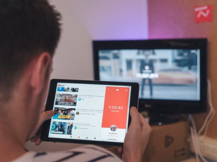man browsing tablet sitting in front of TV