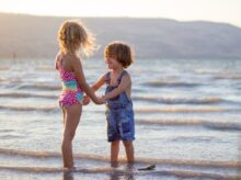 two girls standing on seashore