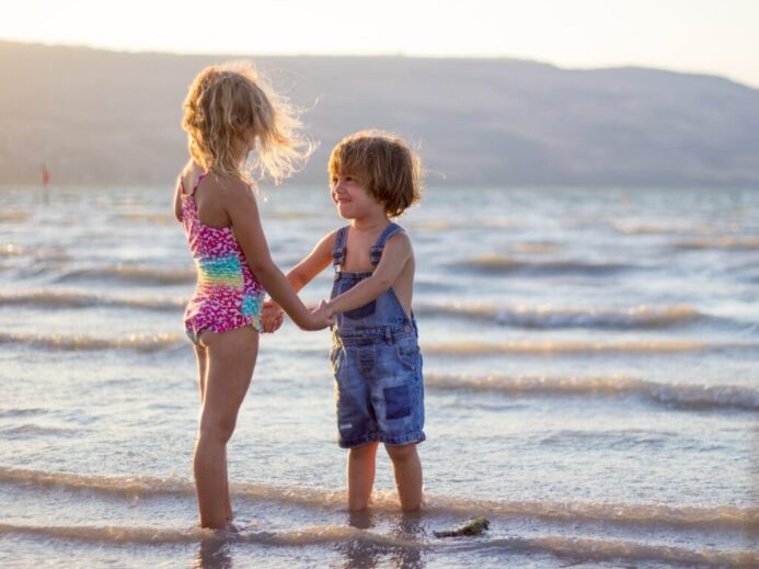 two girls standing on seashore