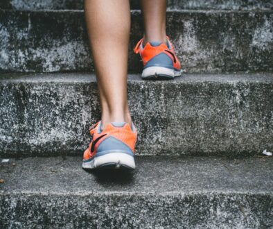 Bruno Nascimento person wearing orange and gray Nike shoes walking on gray concrete stairs