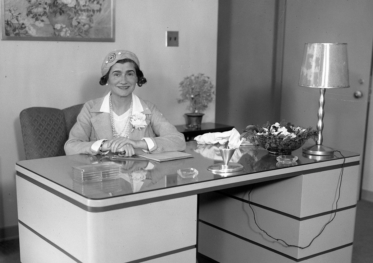 Coco Chanel sedící za stolem