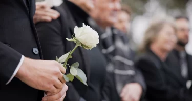 Fotografie z pohřbu, pozůstalí držející kytice