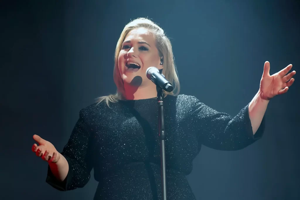 Adele zpívá před mikrofonem v černých šatech