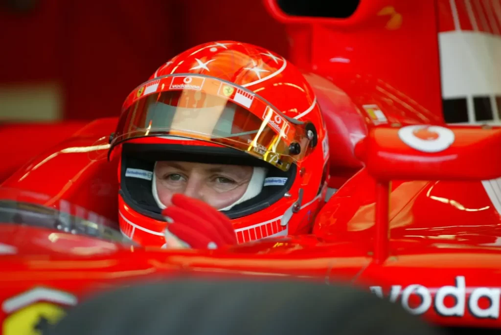 Detailní záběr na Michaela Schumachera v závodní kombinéze Ferrari s helmou 