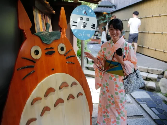 Japonská dívka v tradičním oblečení stojí u postavičky Totora.