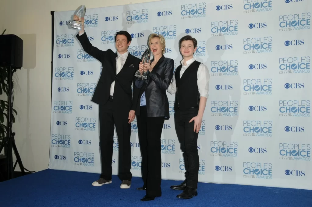 Jane Lynch s trofejí v ruce, po její levici stojí Cory Monteith, který zvedá sošku nad hlavu, a napravo Chris Colfe