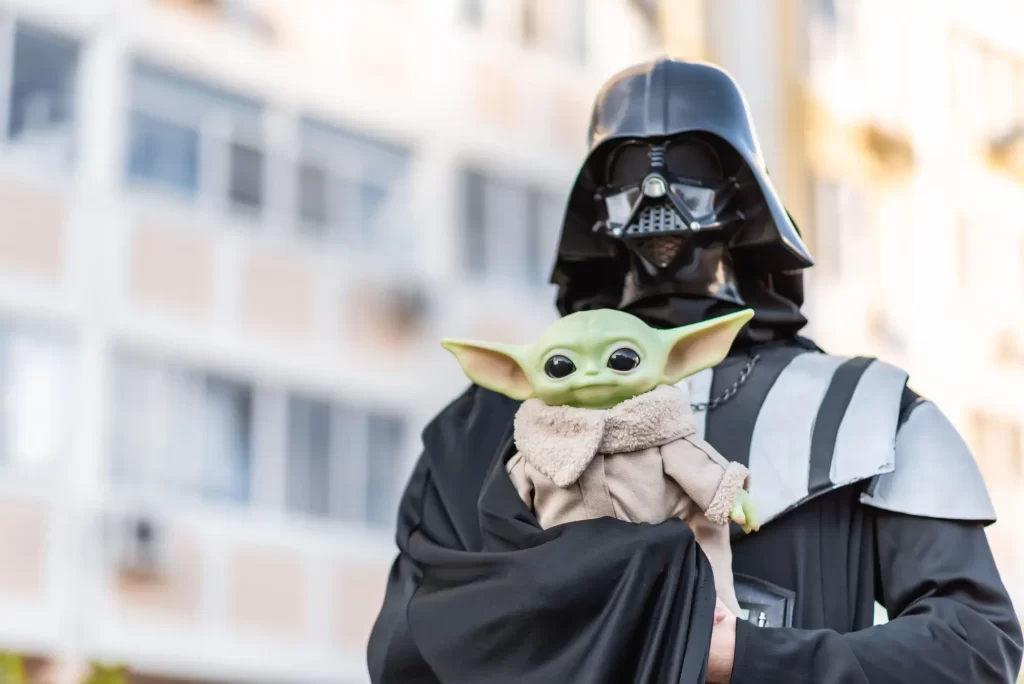 Člověk převlečený za Dartha Vadera drží figurku Baby Yody