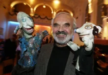 Zdeněk Svěrák usmívající se mezi dvěma loutkami