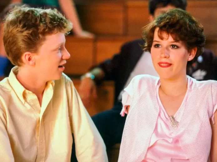 Herečka Molly Ringwald jako Samantha Baker sedí vedle postavy ztvárněné Anthonym Michaelem Hallem ve školní tělocvičně, scéna z filmu Sixteen Candles