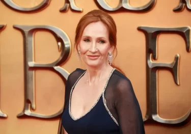 J. K. Rowling v černých večerních šatech na žlutém pozadí.
