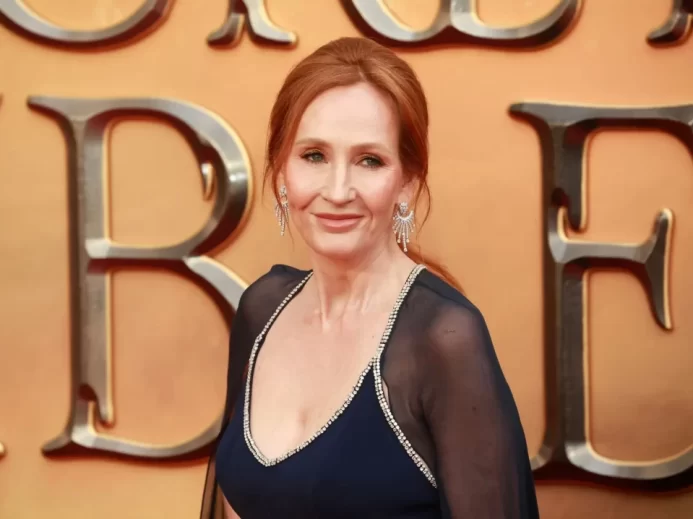 J. K. Rowling v černých večerních šatech na žlutém pozadí.
