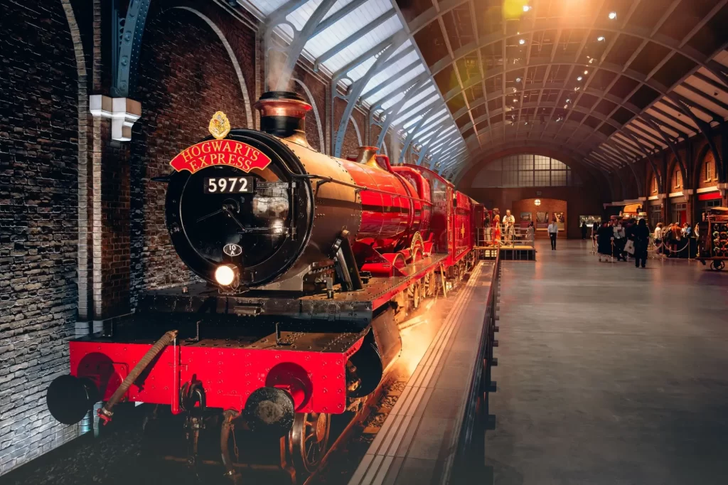 Hogwarts Express s číslem 5972, vystavenou v hale připomínající nádraží King’s Cross. V pozadí se procházejí návštěvníci.