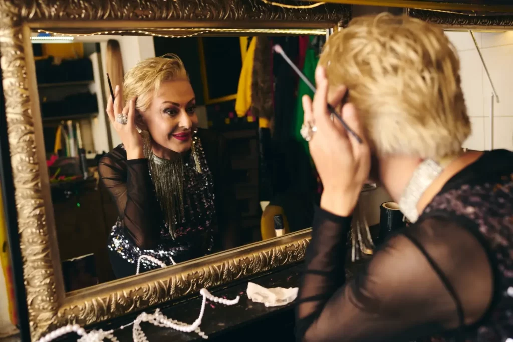 Drag umělec se připravuje u zrcadla v šatně