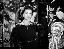 Coco Chanel v černých šatech s perlovým náhrdelníkem