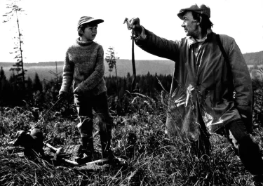 Černobílá scéna z českého filmu s Tomášem Holým a Josefem Kemrem na horské louce