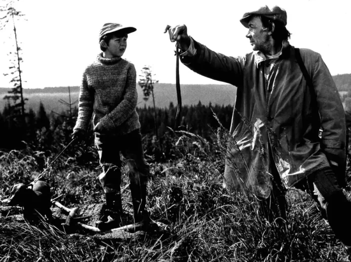 Černobílá scéna z českého filmu s Tomášem Holým a Josefem Kemrem na horské louce
