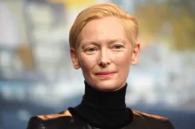 Tildy Swinton v černém roláku a přirozeném líčení, herečka hledí klidně do objektivu během tiskové konference