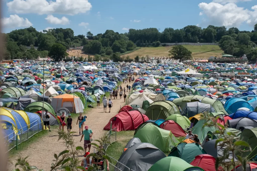 Pohled na rozlehlé stanové městečko s návštěvníky během hudebního festivalu Glastonbury