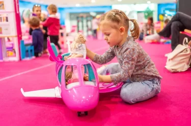 Děvčátko si hraje s barbie v růžové herně