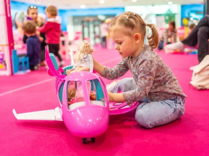 Děvčátko si hraje s barbie v růžové herně