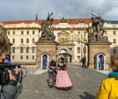 Kameraman, komparzisté a ženy v historických kostýmech před vstupem do Pražského hradu