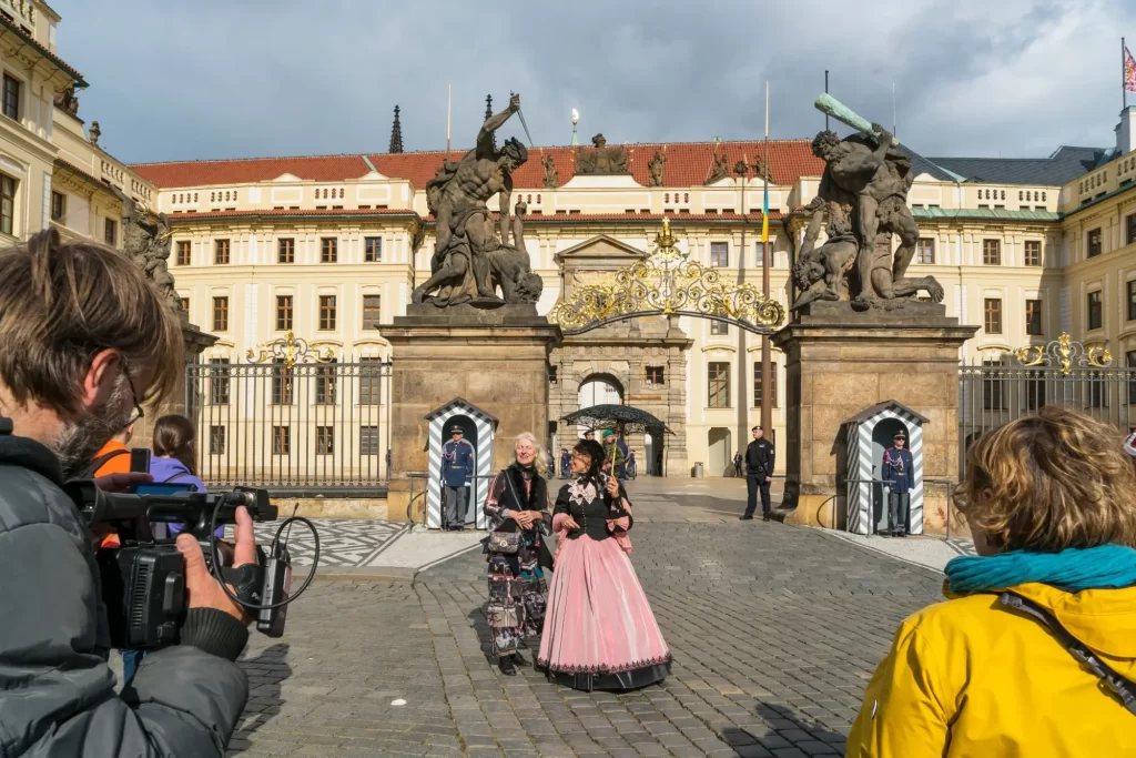 Kameraman, komparzisté a ženy v historických kostýmech před vstupem do Pražského hradu