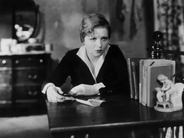 Clara Bow sedící u stolu ve filmové scéně