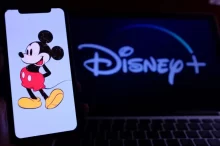 Ilustrace Mickeyho Mouse na mobilním telefonu před obrazovkou s logem Disney+