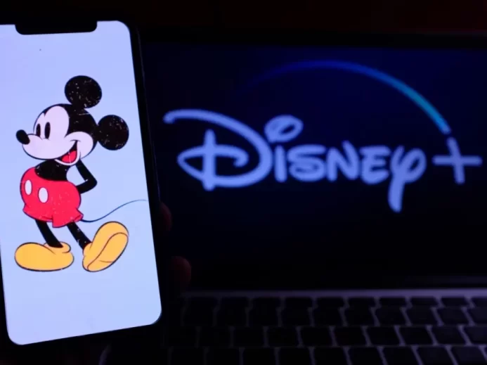 Mickey Mouse se stal symbolem, kvůli němuž Disney bojoval o prodloužení autorských práv Ilustrace Mickeyho Mouse na mobilním telefonu před obrazovkou s logem Disney+