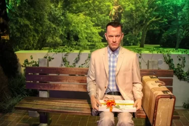 Forrest sedí na slavné lavičce se svým kufrem a krabičkou čokolád, připravený vyprávět svůj neobyčejný příběh.