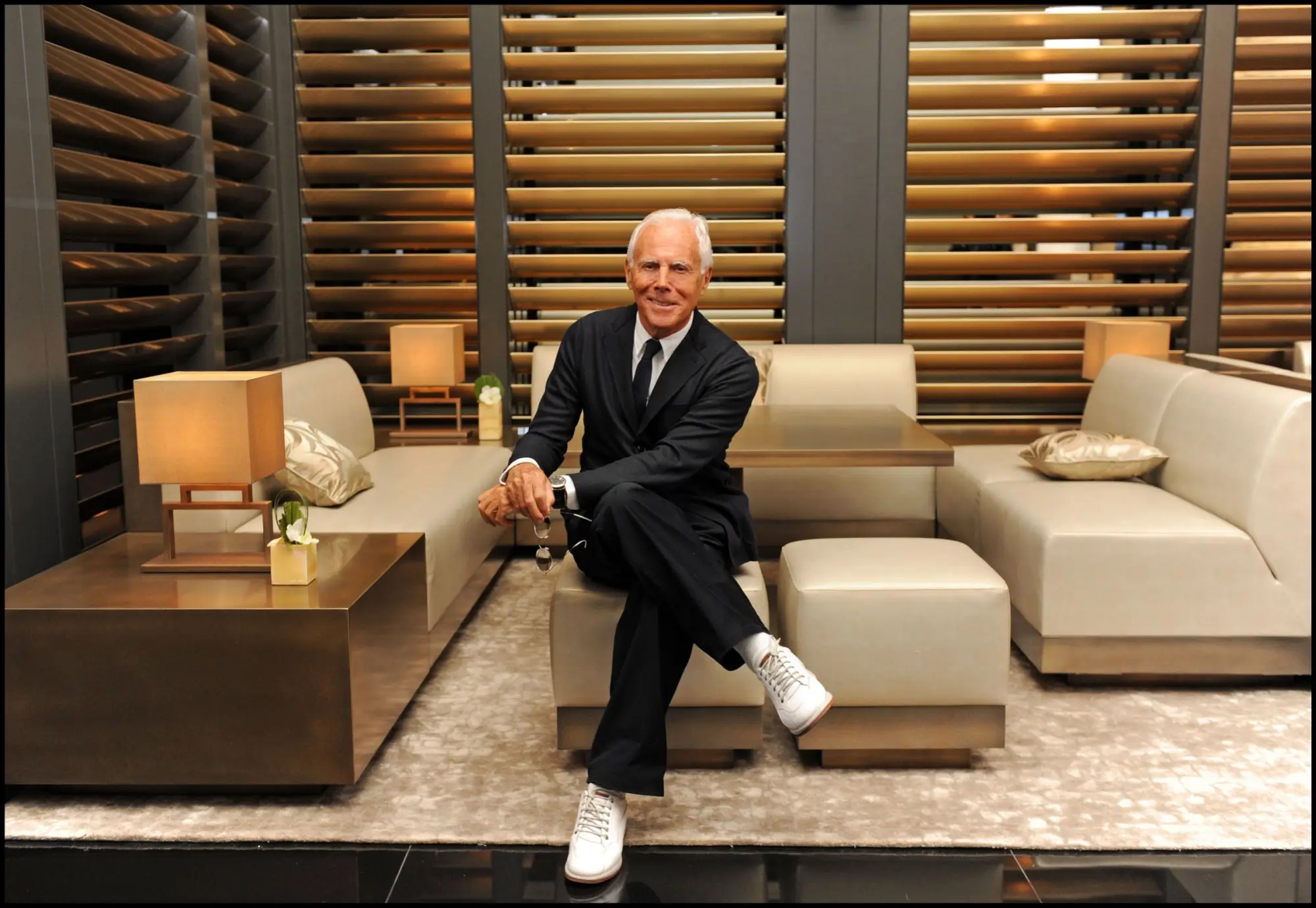 Georgio Armani pózuje v obývacím pokoji v obleku