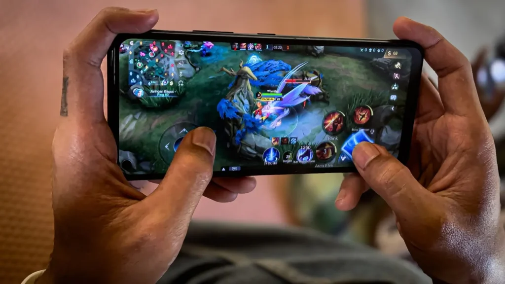 Hráč držící smartphone a hrající mobilní hru v reálném čase