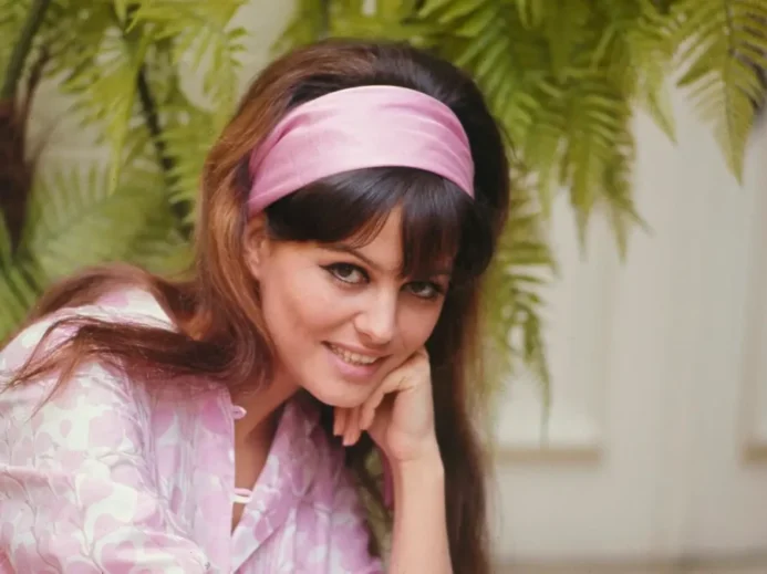 Usměvavá Claudia Cardinale s růžovou čelenkou a jemným líčením