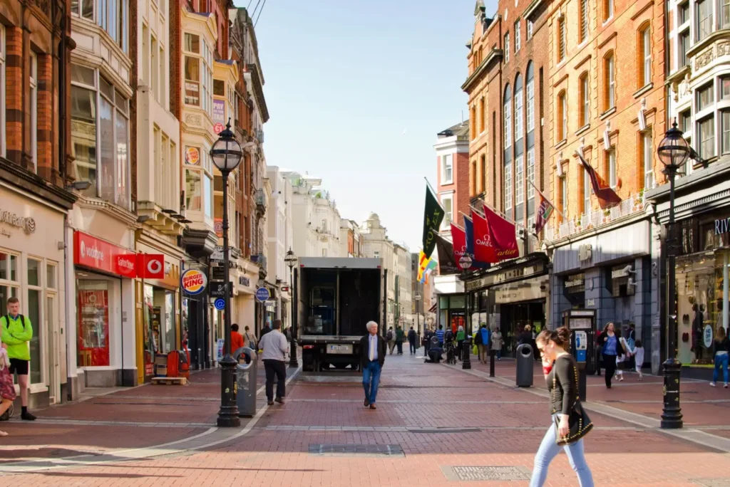 Pohled na rušnou ulici v centru Dublinu s historickými budovami a kolemjdoucími