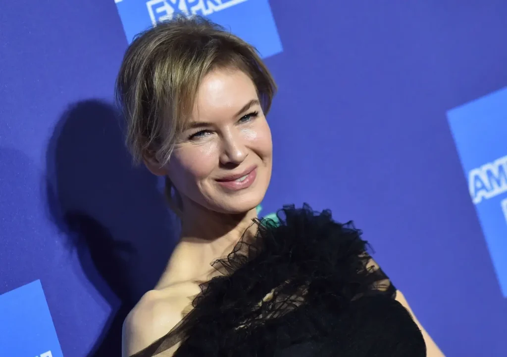 Blond žena v elegantních šatech se usmívá na modrém pozadí