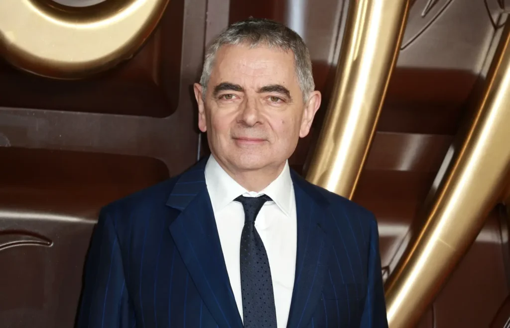 Britský herec Rowan Atkinson v modrém obleku na filmové premiéře