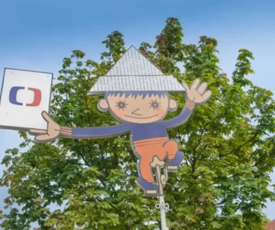Malý kluk s papírovou čepicí, který každý večer zdravil děti před pohádkou Ilustrace postavičky Večerníčka s papírovou čepicí a logem České televize před zelenými stromy