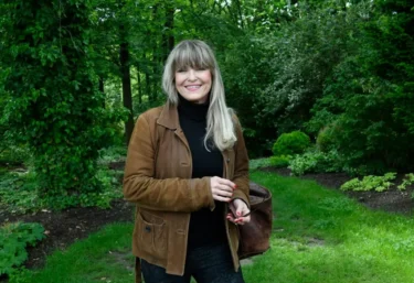 Herečka Chantal Poullain stojí v přírodě v hnědé bundě