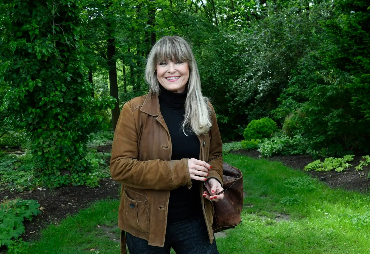 Herečka Chantal Poullain stojí v přírodě v hnědé bundě