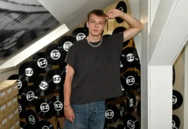 Tomas Sean Pšenička v ležérním oblečení stojí v prostoru s černými vinylovými deskami