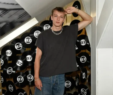 Přirozený talent nové generace: charizma, které nepotřebuje efekty Tomas Sean Pšenička v ležérním oblečení stojí v prostoru s černými vinylovými deskami