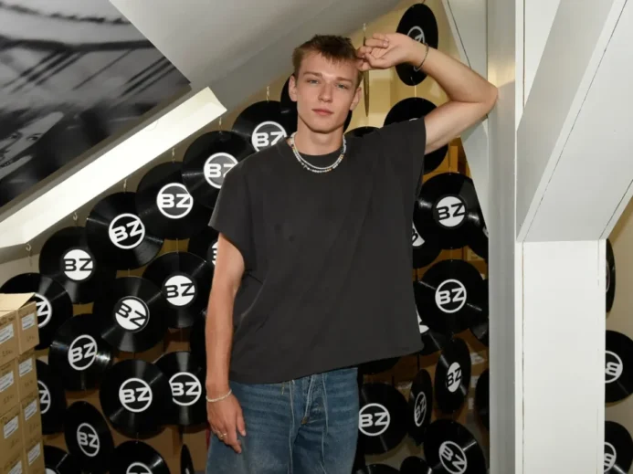 Tomas Sean Pšenička v ležérním oblečení stojí v prostoru s černými vinylovými deskami