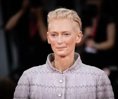 Tilda Swinton v jemně fialovém saku s perlovými knoflíky pózuje před fotografy
