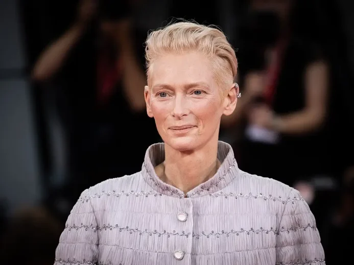 Tilda Swinton v jemně fialovém saku s perlovými knoflíky pózuje před fotografy