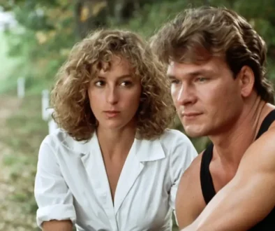 Man in a black sleeveless shirt and a white-blouse woman sit together on a park path, looking thoughtful.