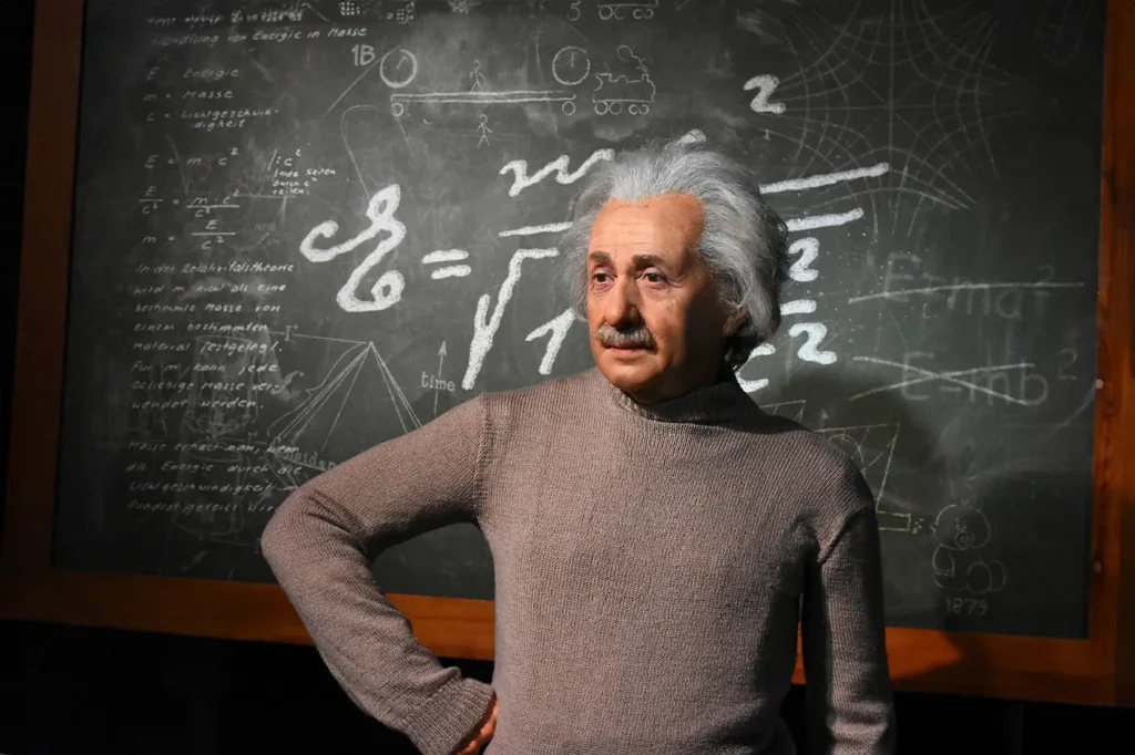 Slavný vědec stojí před tabulí s matematickými výpočty.