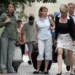 Skupinka lidí s kufry jde po ulici