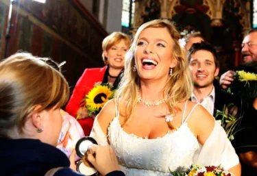 Žena se světlými vlasy ve svatebních šatech se směje