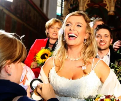 Žena se světlými vlasy ve svatebních šatech se směje