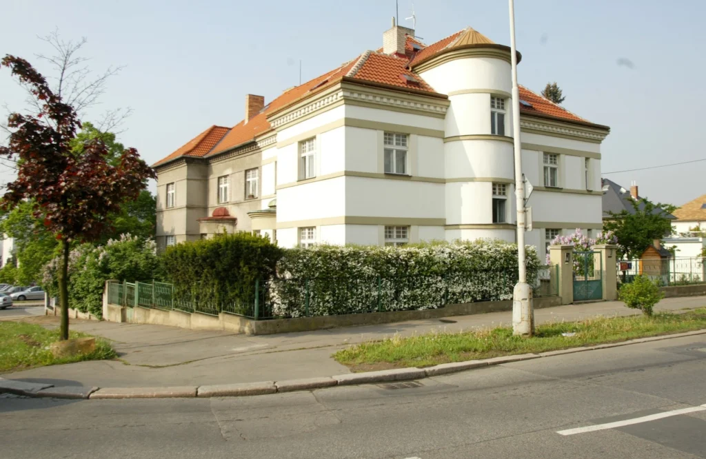 Vila u silnice, má bílou fasádu a červenou střechu